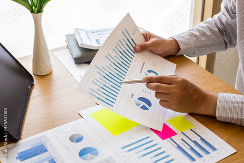 Young businessman pointing to last quarter's earnings and planning revision of business finances next quarter, businessman pointing to past company volatility, businessman planning ideas.