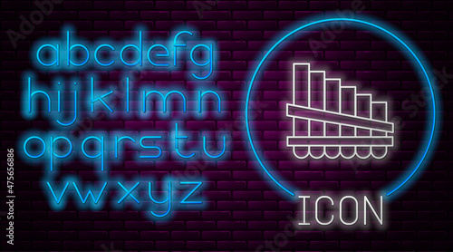 Glowing neon line Pan flute icon isolated on brick wall background. Traditional peruvian musical instrument. Zampona. Folk instrument from Peru, Bolivia and Mexico. Neon light alphabet. Vector