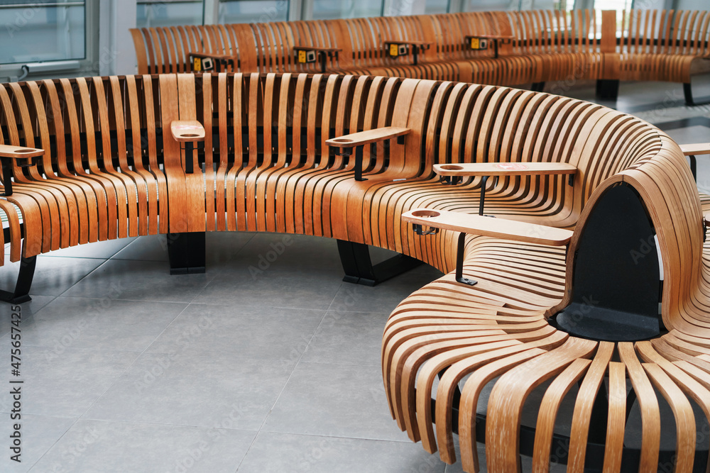Modern designer curved bench made of natural wood in the airport terminal. Modern designer curved bench made of natural wood in the airport terminal.