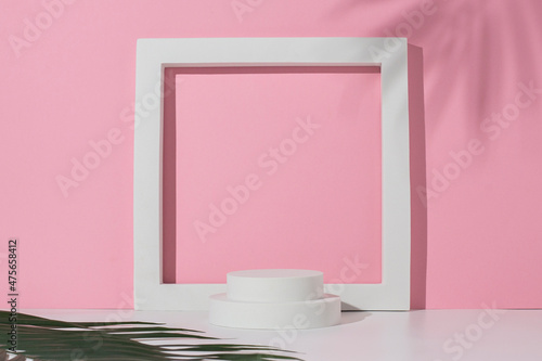 White square podium, circles for presentation and a leaf of a palm tree on a white pink background