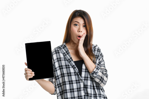Portrait studio shot of Asian happy pretty long hair female model in plaid shirt standing smiling look at camera showing presenting blank screen tablet for ads and hold thumb up on white background