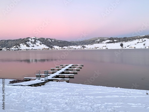 Sunset over lake Sihlsee in Switzerland, canton Schwyz in winter. There is empty mooring place for boats veered with snow. pastel sky is on the background and colors reflect partly on water surface. photo
