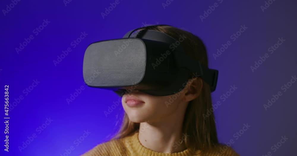 A girl in virtual reality glasses plays an online game, making hand movements A girl in virtual reality glasses plays an online game, making hand movements