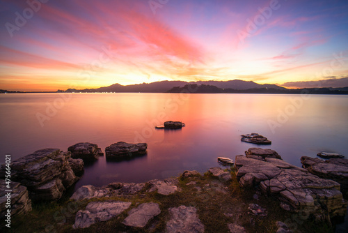 Beautiful sunset view with the purple sky and white floating rock on the water for background and wallpaper