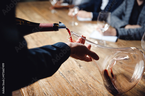 Photos Close-up sommelier pouring red wine into decanter at master class in restaurant