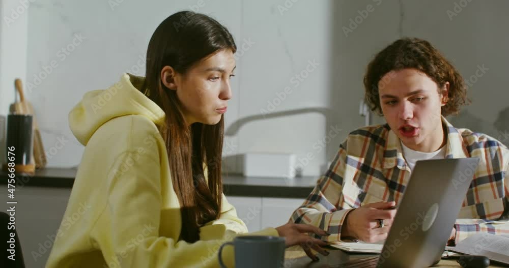 Young couple are engaged at home with books and an open laptop Young couple are engaged at home with books and an open laptop