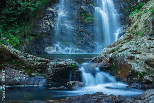 фотографія waterfall flowing streams through rocks with calm blurred water surface long exp
