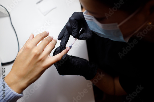 Manicure process female hands finger nails polish. Beautician in gloves at nail salon
