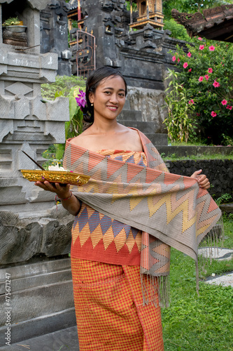 Portrait young woman with balinese face, wearing dress traditional Bali sarong in home temple.  photo