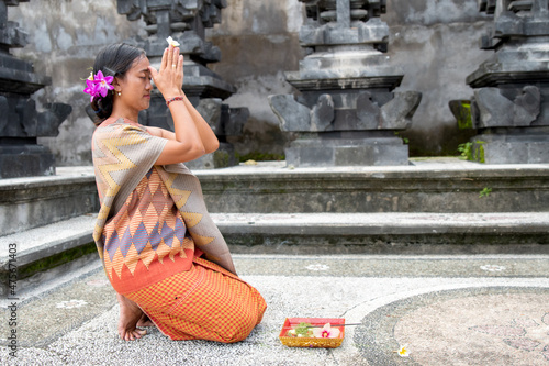 Portrait young woman with balinese face praying in home temple.  photo