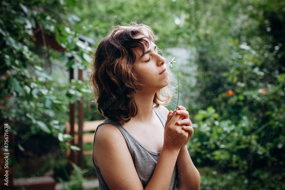 Teenager Girl sniffing chamomile flower in the forest. Natural beauty. Candid moments Teenager Girl sniffing chamomile flower in the forest. Natural beauty. Candid moments