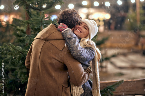 A young couple in love is in hug while enjoying christmas holidays and walking the city. Christmas, New Year, holiday, love