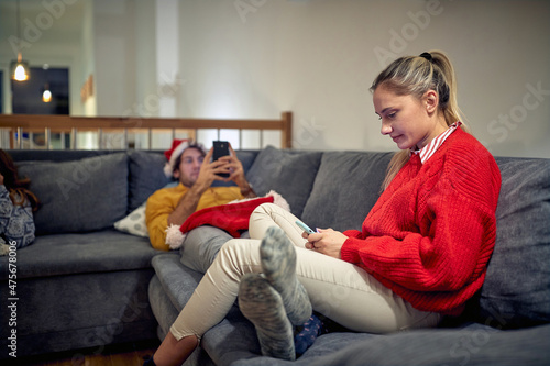 Bored Christmas. Couple online with smartphones.