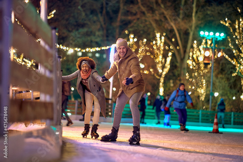 Фотография Jolly multiethnic couple enjoying ice skating