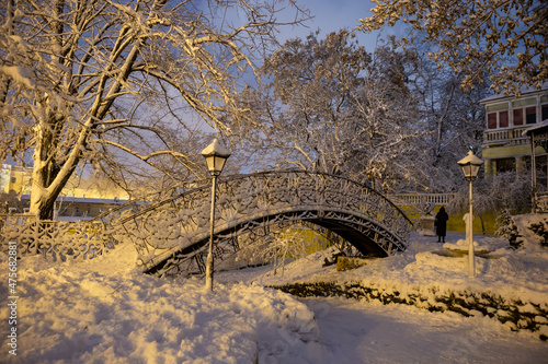 Snowy city park with bridge, trees, lamps, night time, Odessa, Ukraine landmark.