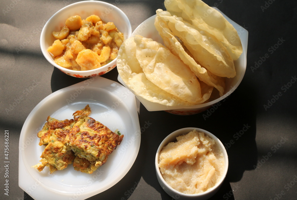 Alur dom, egg omelette and halwa with. luchi on black background. Bengali traditional breakfast. Alur dom, egg omelette and halwa with. luchi on black background. Bengali traditional breakfast.