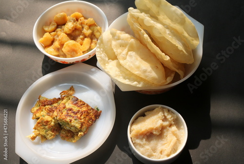 Alur dom, egg omelette and halwa with. luchi on black background. Bengali traditional breakfast. photo