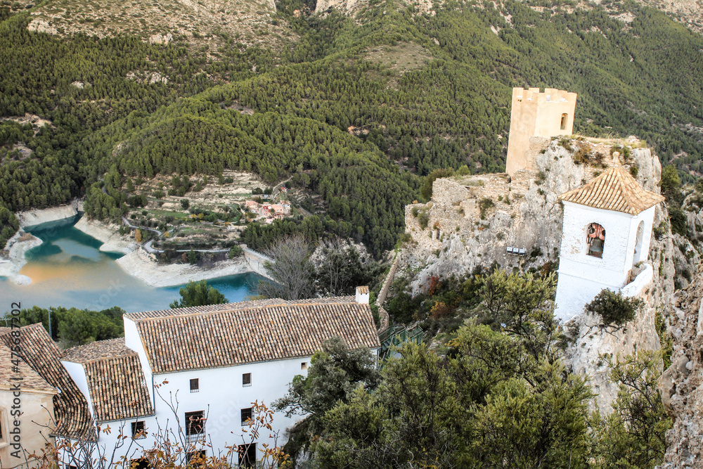 Guadalest village surrounded by vegetation, the reservoir and the Castle and bell tower