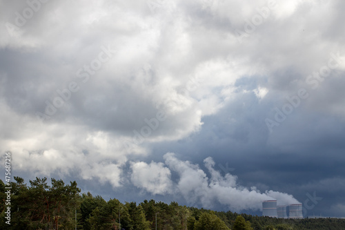 View of the blue sky and white clouds.Factory pipes of a nuclear power plant with thick white smoke on the shore of the Gulf of Finland, polluting the environment.