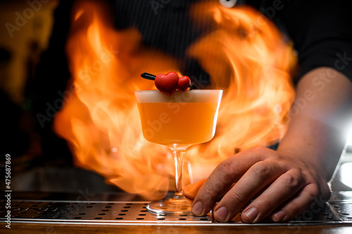 bartender holds transparent glass with yellow delicious alcoholic drink photo