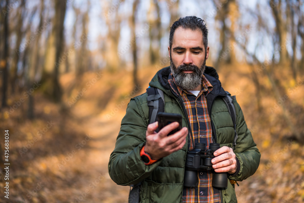 Image of hiker using phone while spending time in nature.