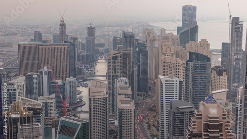 Skyline view of Dubai Marina showing canal surrounded by skyscrapers along shoreline day to night timelapse. DUBAI, UAE
