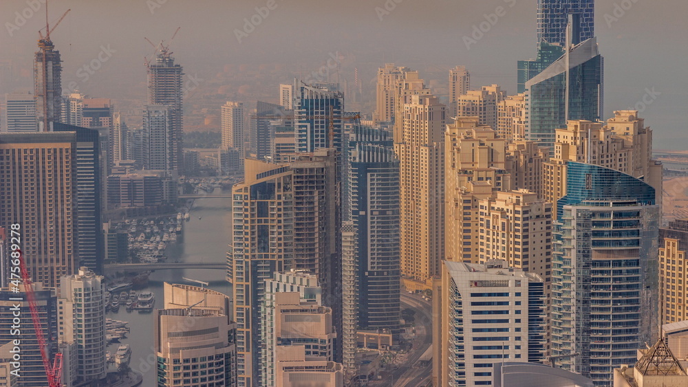 Fototapeta premium Skyline panoramic view of Dubai Marina showing an artificial canal surrounded by skyscrapers along shoreline timelapse. DUBAI, UAE