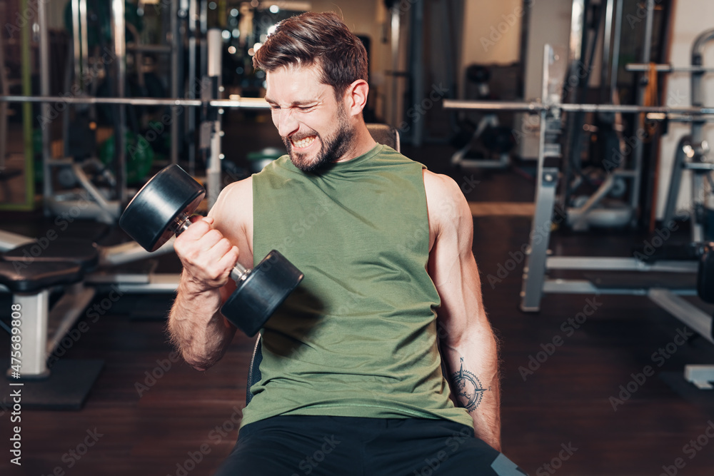 visible pain at face of this sportive man while lifting dumbbells and effort gaining muscles visible pain at face of this sportive man while lifting dumbbells and effort gaining muscles