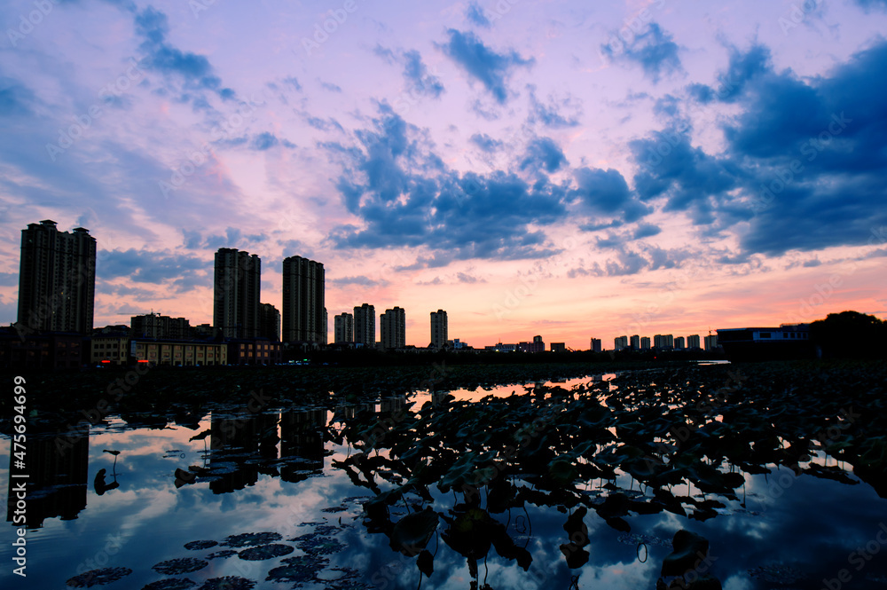 The river in the city park reflects the city skyline and a beautiful and spectacular sunset glow.