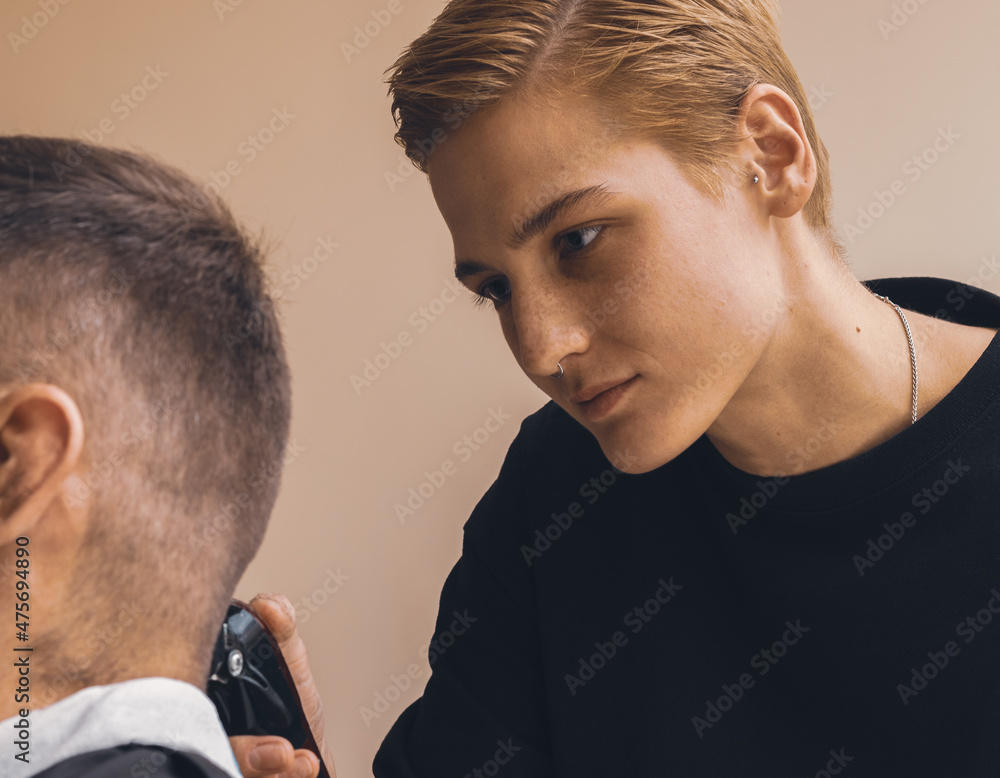 Fototapeta premium A female barber is styling a male client's hair in her salon