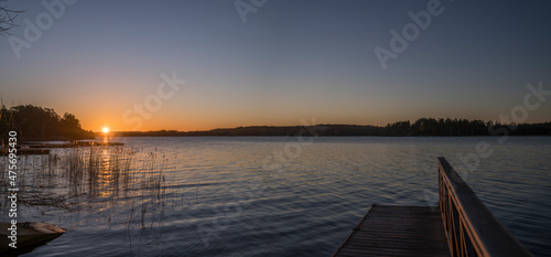 Morning view at sunrise, silhouettes, a jetty at a pier and reflections at the lake Mälaren in the district Bromma in a sunny day in Stockholm