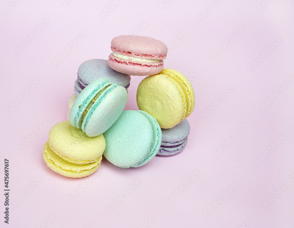 A lot of cakes, pasta of different colors colorful blue, yellow, green, round pasta on a purple background lie one on one. French sweet cookies. For the holiday, birthday, advertising confectioners. A lot of cakes, pasta of different colors colorful blue, yellow, green, round pasta on a purple background lie one on one. French sweet cookies. For the holiday, birthday, advertising confectioners.
