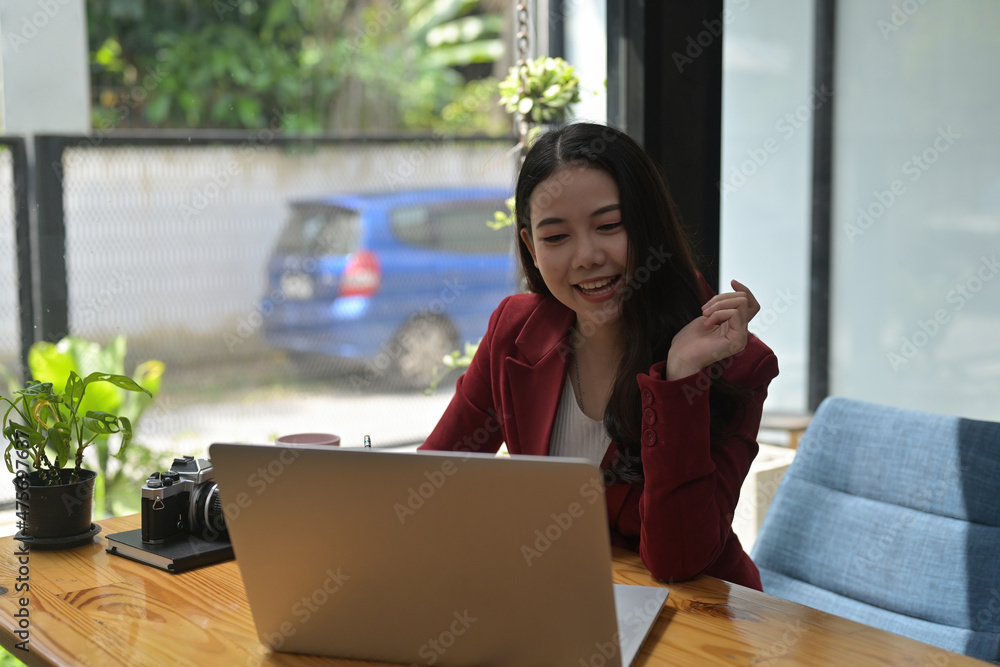 Photo of a beautiful businesswoman using a computer laptop at the wooden working desk with the comfortable living room as a background. Photo of a beautiful businesswoman using a computer laptop at the wooden working desk with the comfortable living room as a background.