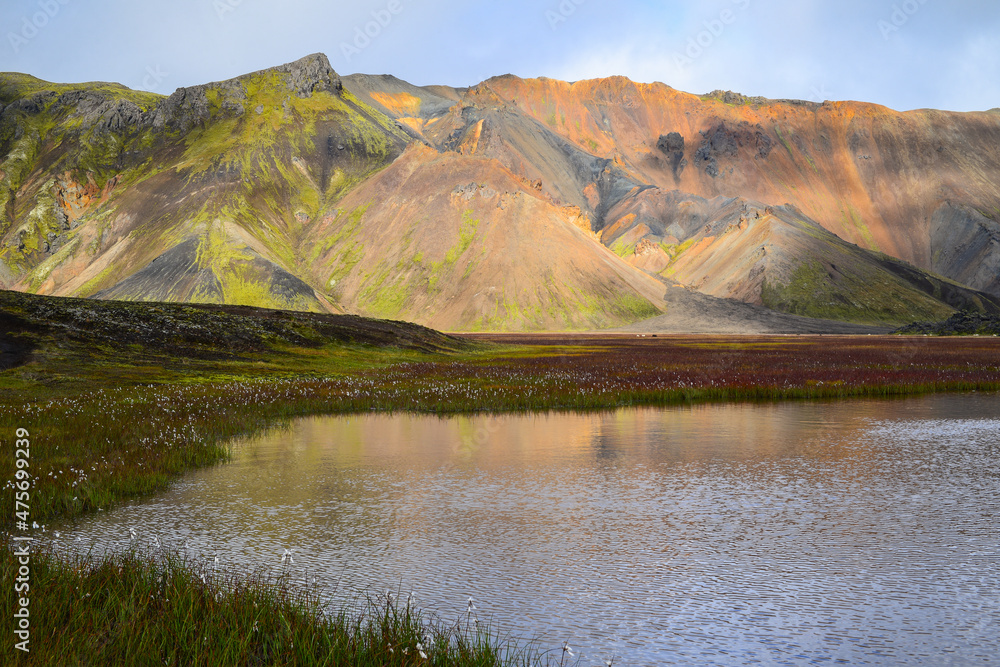 A small lake amidst the rhyolite mountains and green meadows of Landmannalaugar, Fjallabak Nature Reserve, Central Highlands, Iceland