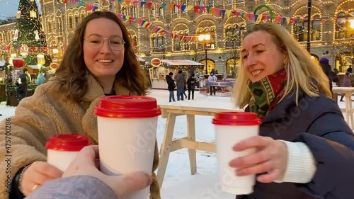 Christmas Market in Moscow on Red Square: two cheerful young women with cardboard cups of mulled wine 