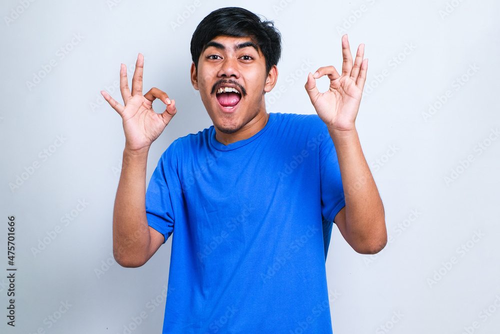 Asian man smiling positive doing ok sign with hand and fingers. successful expression. Asian man smiling positive doing ok sign with hand and fingers. successful expression.