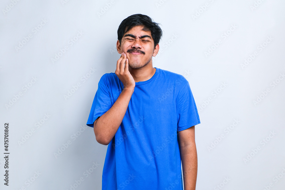 Asian man touching mouth with hand with painful expression because of toothache or dental illness on teeth Asian man touching mouth with hand with painful expression because of toothache or dental illness on teeth