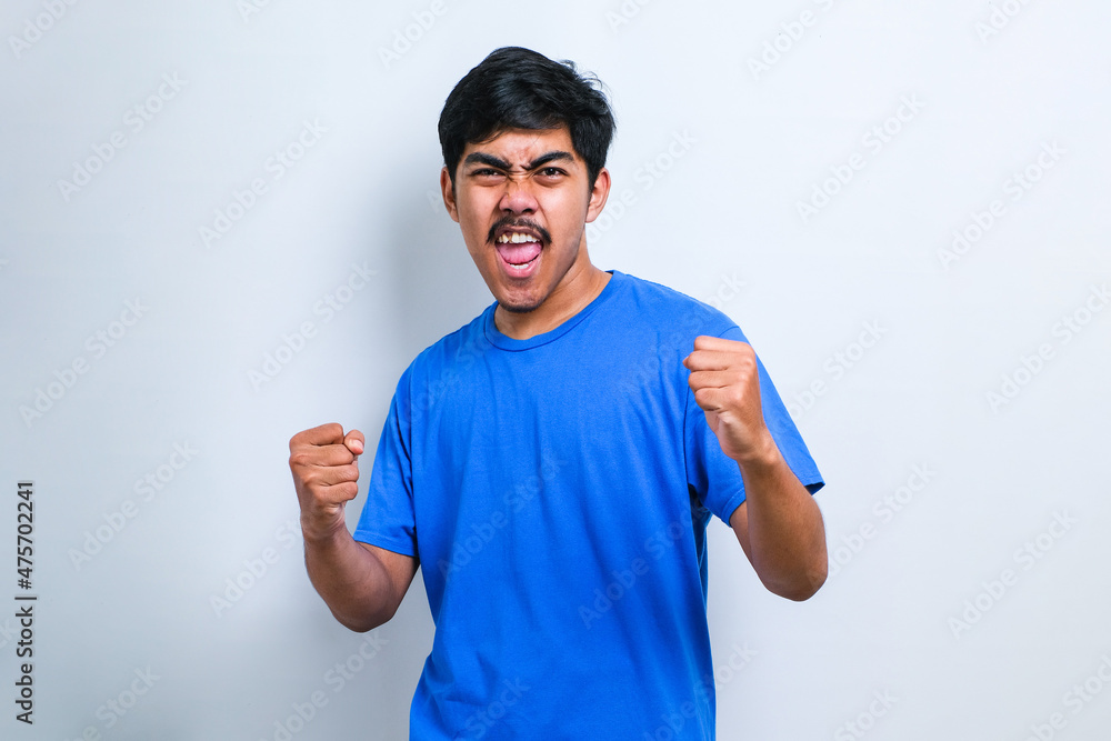 Fototapeta premium Asian man very happy and excited doing winner gesture with arms raised, smiling and screaming for success