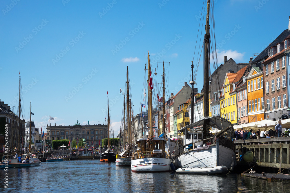Nyhavn is a waterfront and canal in Copenhagen, Denmark. Colourful facades of houses and old ships along the canal. Wooden ships moored in the canal