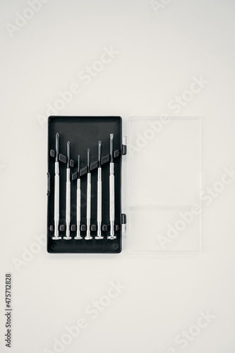 Container with small screwdrivers for watches on isolated white background