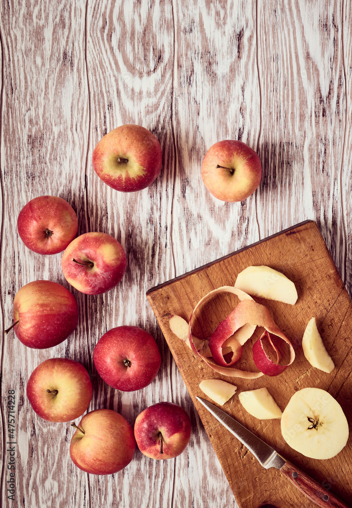 Juicy red apples and a curl of apple peel lying on a wooden table, stylized, top view Juicy red apples and a curl of apple peel lying on a wooden table, stylized, top view