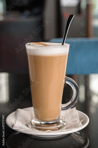A glass of coffee latte on a table against a blurred background.