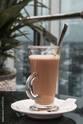 A glass of coffee latte on a table against a blurred background.