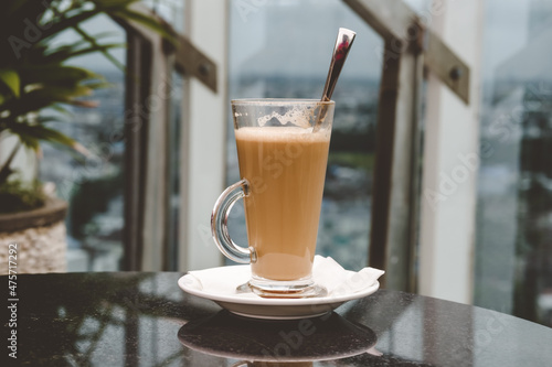 A glass of coffee latte on a table against a blurred background.
