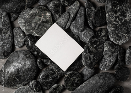 Photography white blank  business card on black stones or galet ,concept of zen spa or sauna branding