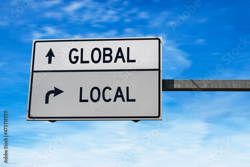 Wallpaper Mural Road sign with words global and local. White two street signs with arrow on metal pole on blue sky background. Torontodigital.ca