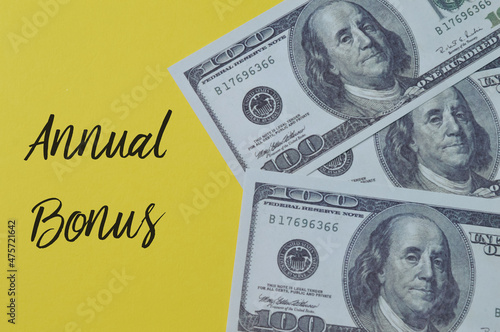 Money banknotes on a yellow background with text ANNUAL BONUS