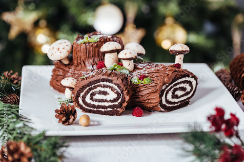 Tableau sur toile French dessert called Yule log or bûche de Noël with merengue mushrooms and mint leaves on top of chocolate glazing