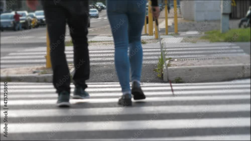 back view of young man helping his friend with a disability to cross the street back view of young man helping his friend with a disability to cross the street