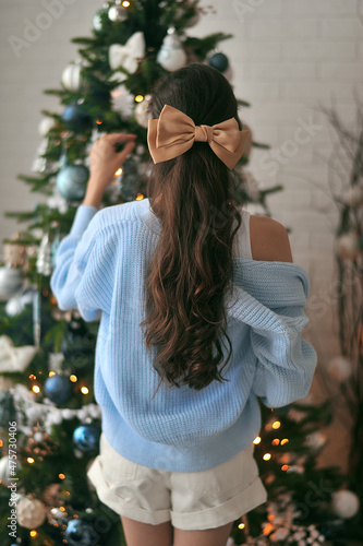 Beautiful woman in a sweater decorates the christmas tree